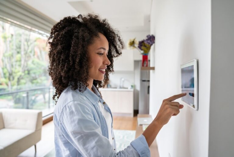 Woman Adjusting Temperature On Smart Thermostat